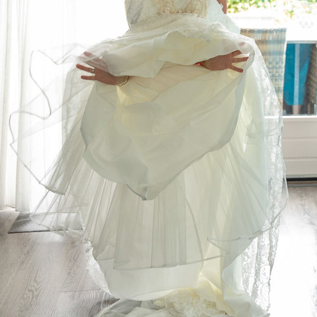 Bruidsfotografie; trouwfotograaf; De moeder van de bruid houdt de trouwjurk op, zodat haar dochter erin kan stappen.
