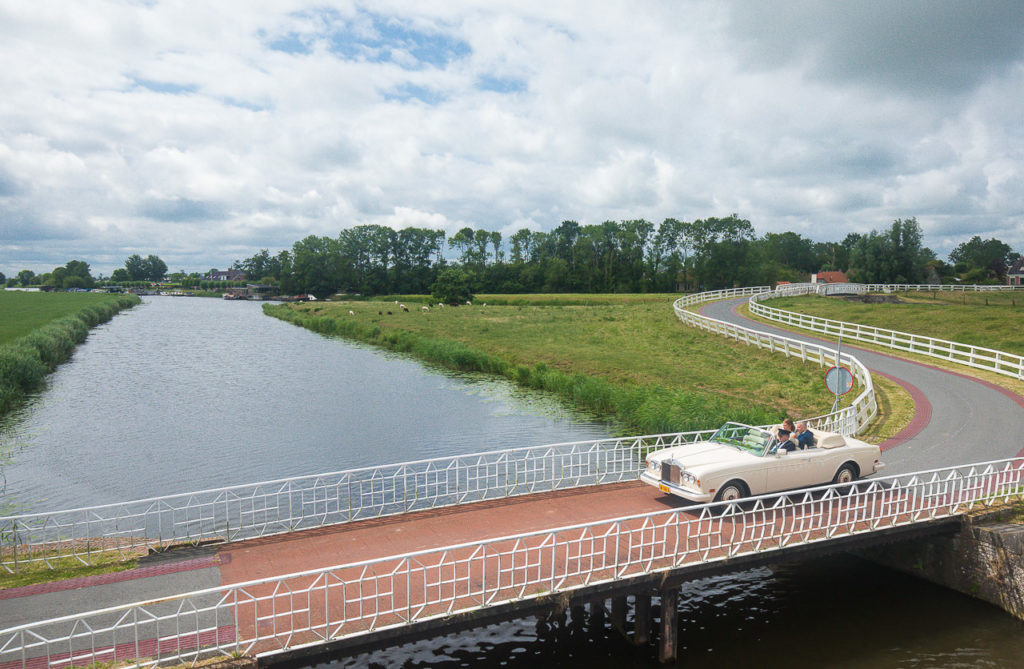 Bruidsfotografie-firstsight-Aduarderzijl-Groningen-KleijenCo-11 Bruidsfotografie; trouwfotograaf; Het bruidspaar, in de trouwauto met chauffeur, rijdt door Aduarderzijl