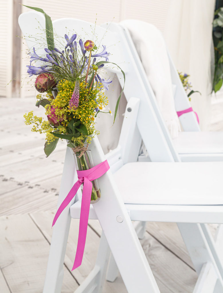 Bruidsfotografie-garnwerdaanzee-Groningen-KleijenCo-1 Bruidsfotografie; trouwfotograaf; Een detailfoto van een boektje bloemen wat is vastgemaakt aan een stoel aan het gangpad