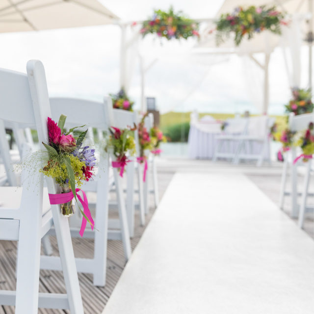 Bruidsfotografie; trouwfotograaf; Boeketjes bloemen in de stijl van het bruidsboeket, bevestigd aan de stoelen van de gasten
