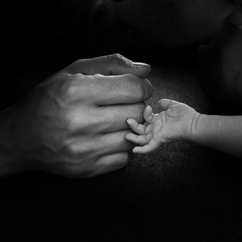 Handen van papa en pasgeboren zoon tegen elkaar