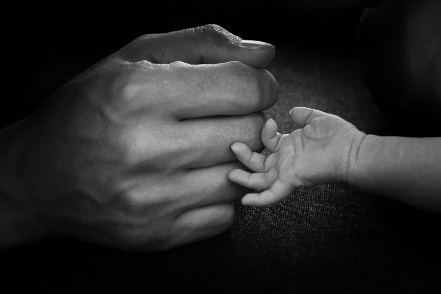 Handen van papa en pasgeboren zoon tegen elkaar